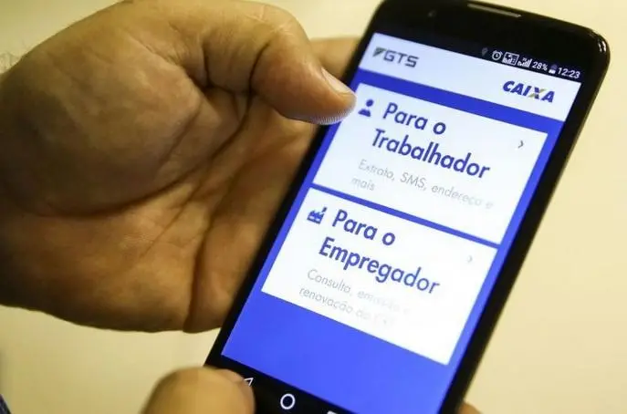 Mão mexendo no celular usando o aplicativo do FGTS